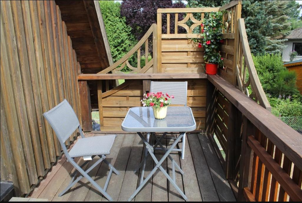 Holzbalkon mit Bistrotisch und zwei Stühlen