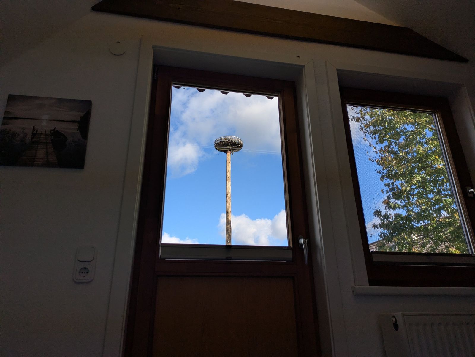 Blick aus dem Schlafzimmer auf das Storchennest vor blauem Himmel