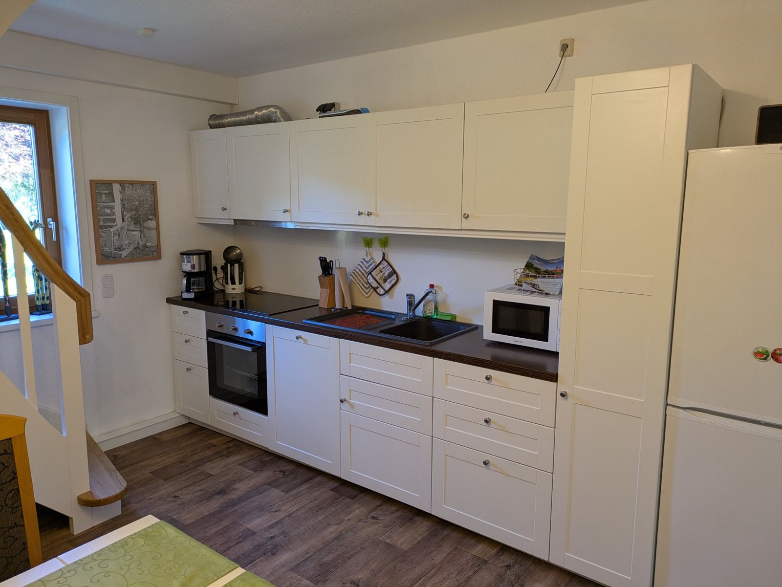 Weiße Einbauküche mit Backofen, Mikrowelle und Kühlschrank