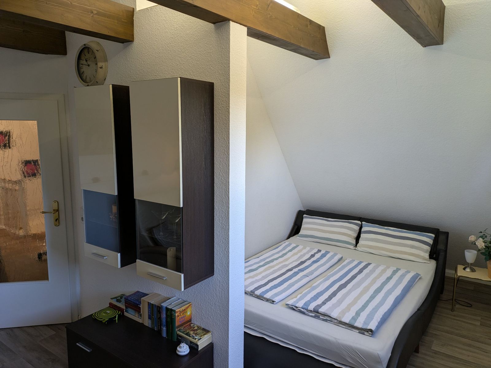 Doppelbett unter Holzbalken im Obergeschoss
