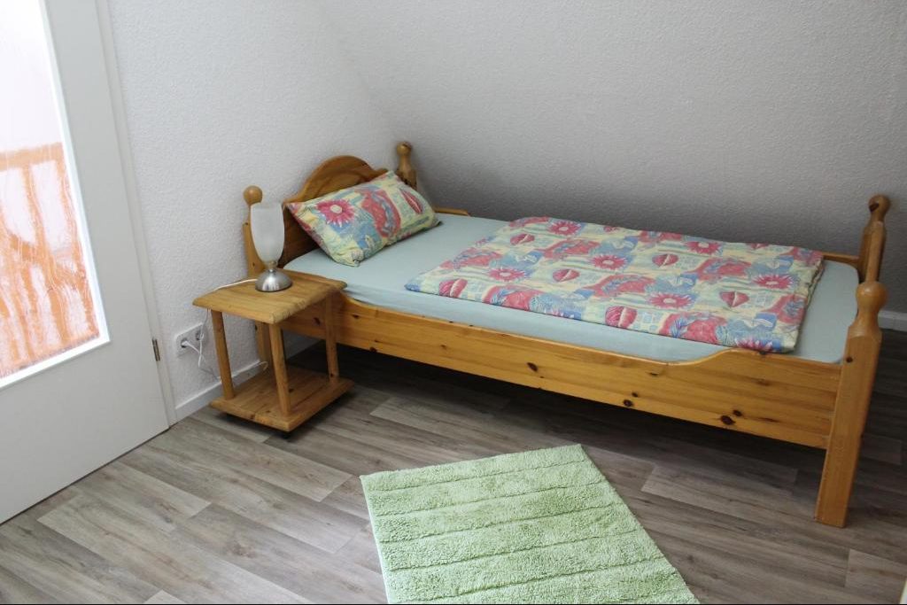 Einzelbett aus Kiefernholz mit Nachttisch und Lampe